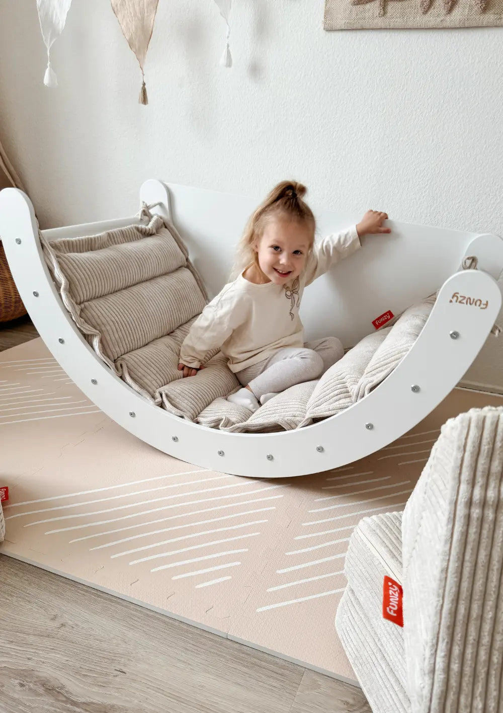 Mädchen sitzt auf dem Funzy Kletterbogen Birke Weiß inkl. Auflage Cord Creme Beige