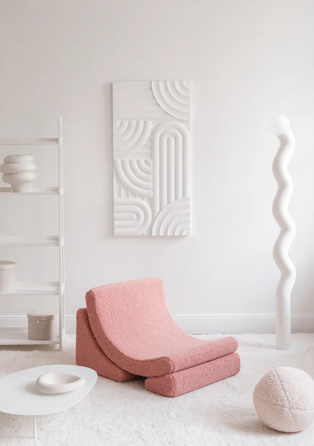 Der altrosafarbene Wigiwama Kindersessel Moon Chair Teddy Guava aus kuschligem Plüsch steht frei auf einem hellen Teppich in einem weißen, modern eingerichteten Zimmer.