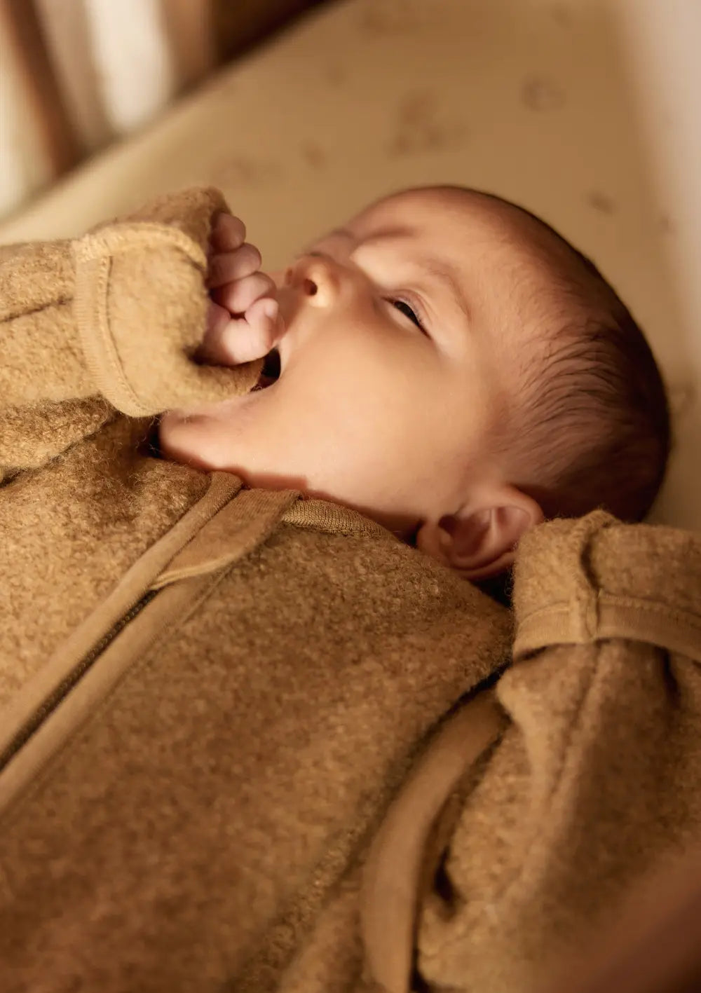 Nahaufnahme eines Babys, das den Jollein Merino Baby Schlafsack mit abnehmbaren Ärmeln TOG 2,0-2,5 Dark Hazel trägt