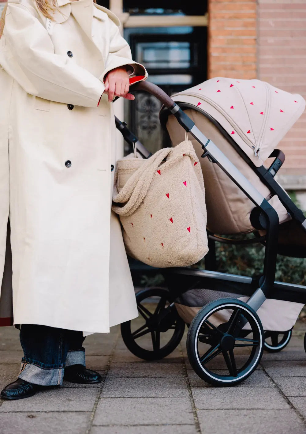 Nahaufnahme der am Griff des Buggys befestigten, flauschigen Wickeltasche mit Herzen aus dem Joolz Kinderwagen-Set Day5 x Studio Noos Sandy Taupe.