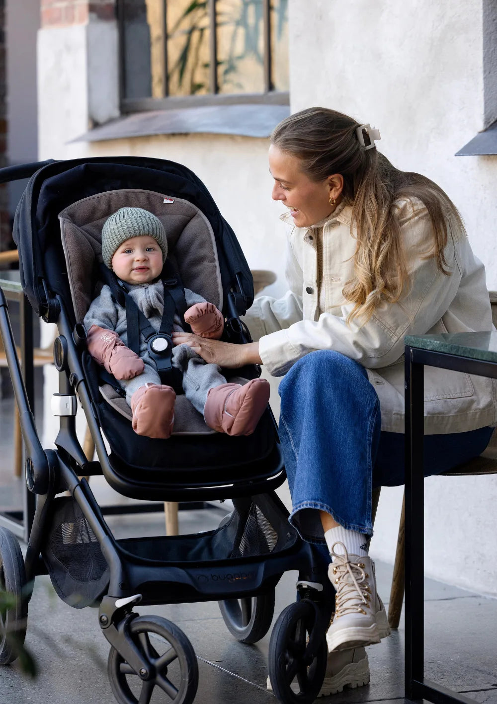Mutter schaut zu ihrem Kind, das im Kinderwagen sitzt und die rosafrbenen Voksi Baby Fäustlinge  und Booties in Blush Pink trägt